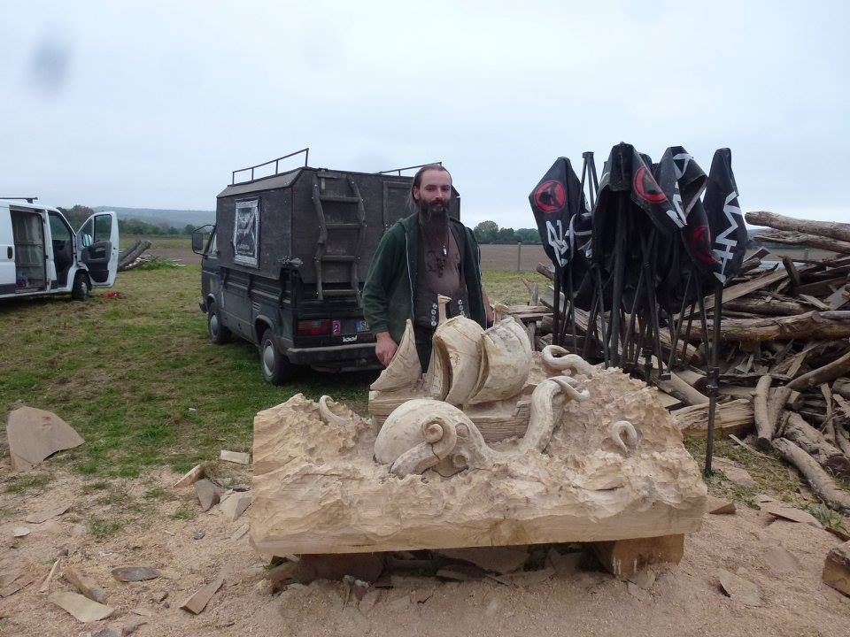 Holzbilderhauer Martin Reichmann und seine Figur der Oktopode. Im Hintergrund sein Kraftfahrzeug.