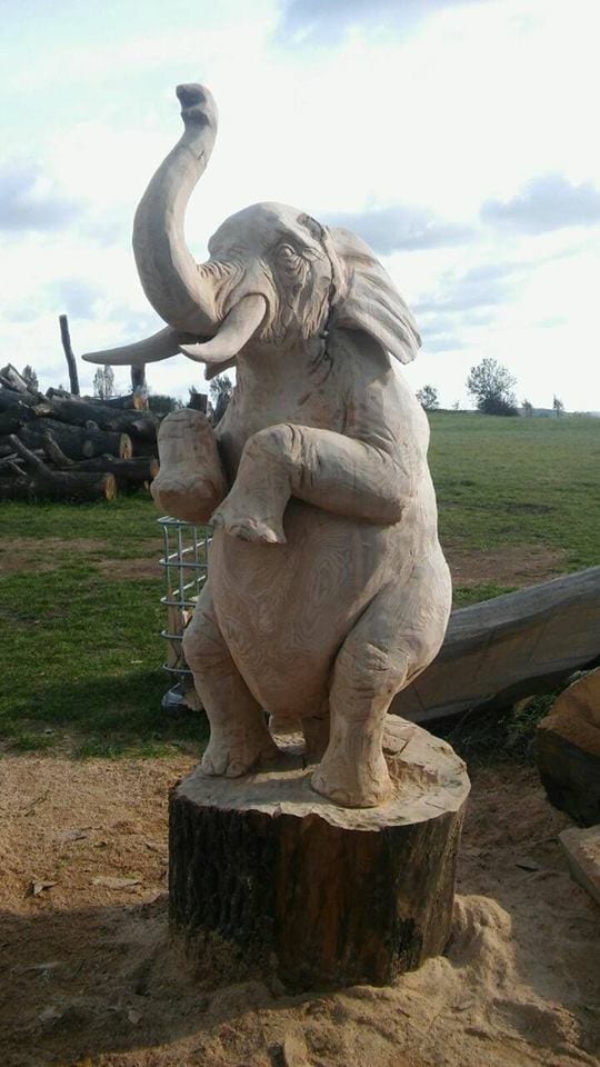 Geschnitzte Figur aus Holz | Elefant stehend auf 2 Beinen und Rüssel steckt sich nach oben. Mit Blick von der linke Seite